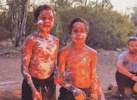Shirtless boys covered in white paint