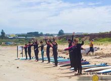 Students stretching at the beach with surfboards